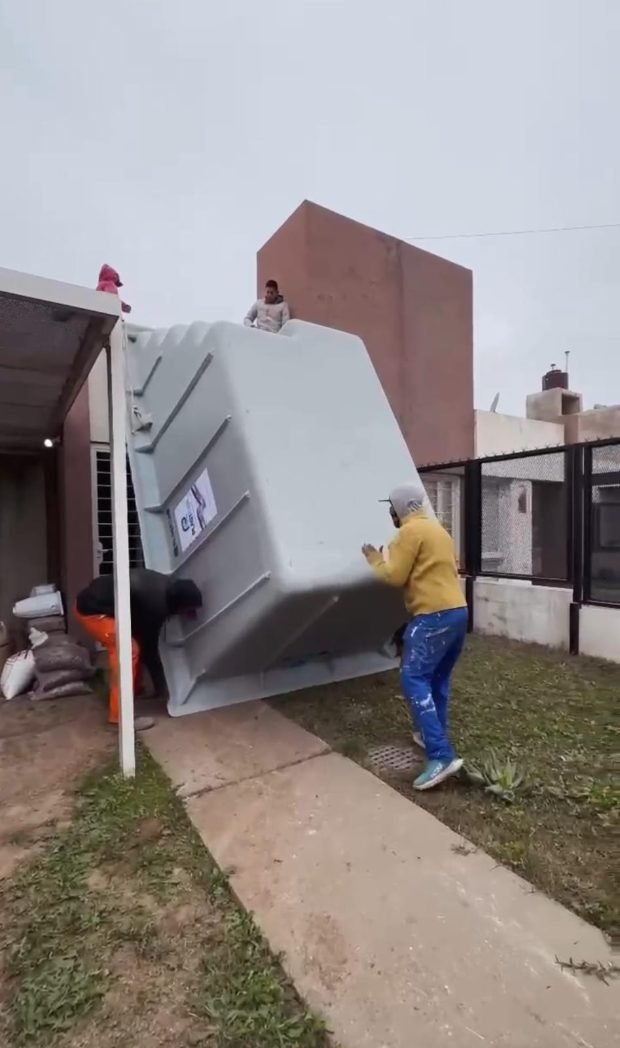 La cuadrilla pasando el casco de la piscina por el costado de la casa